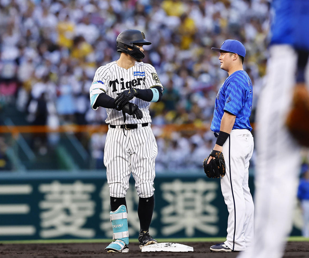 阪神対DeNA 2回裏阪神無死、佐藤輝は左越えに二塁打を放ち、牧（右）と言葉を交わす（撮影・藤尾明華）