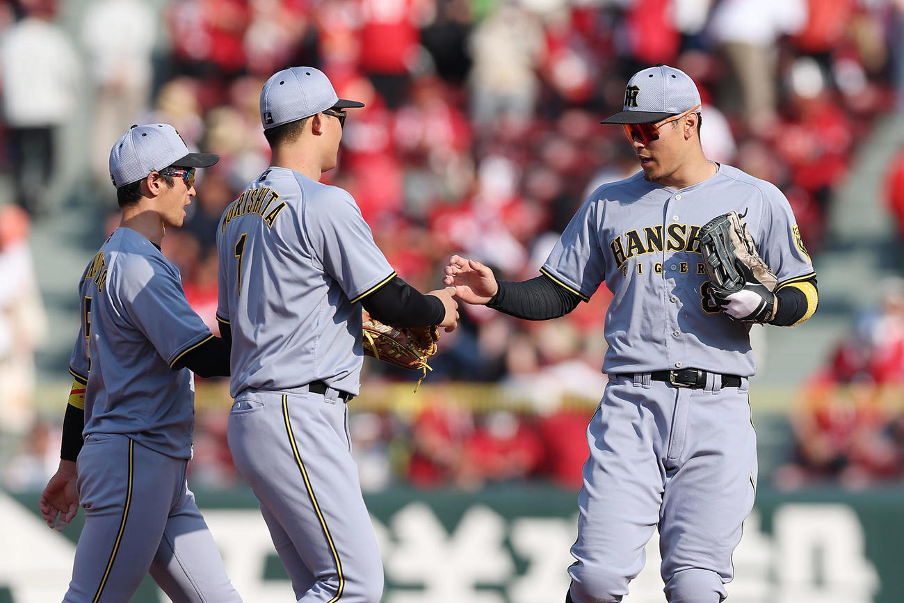 広島対阪神　広島に3連勝し、タッチを交わす佐藤輝（右）と森下。左は近本（撮影・前田充）