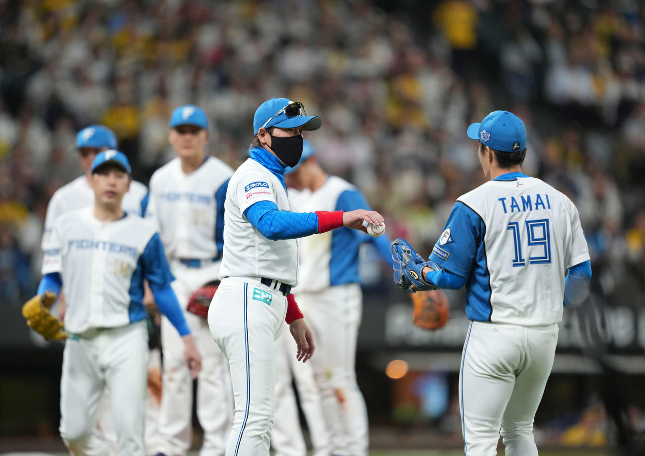 日本ハム対阪神　6回、玉井（右）にボールを渡す新庄監督（中央）。後方は加藤貴（撮影・井上学）