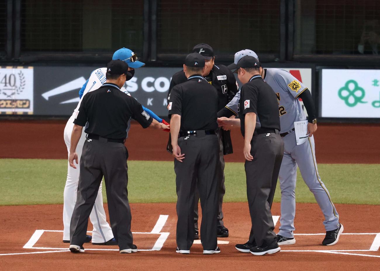 日本ハム対阪神　メンバー表で手を合わせる両監督と審判団（撮影・黒川智章）