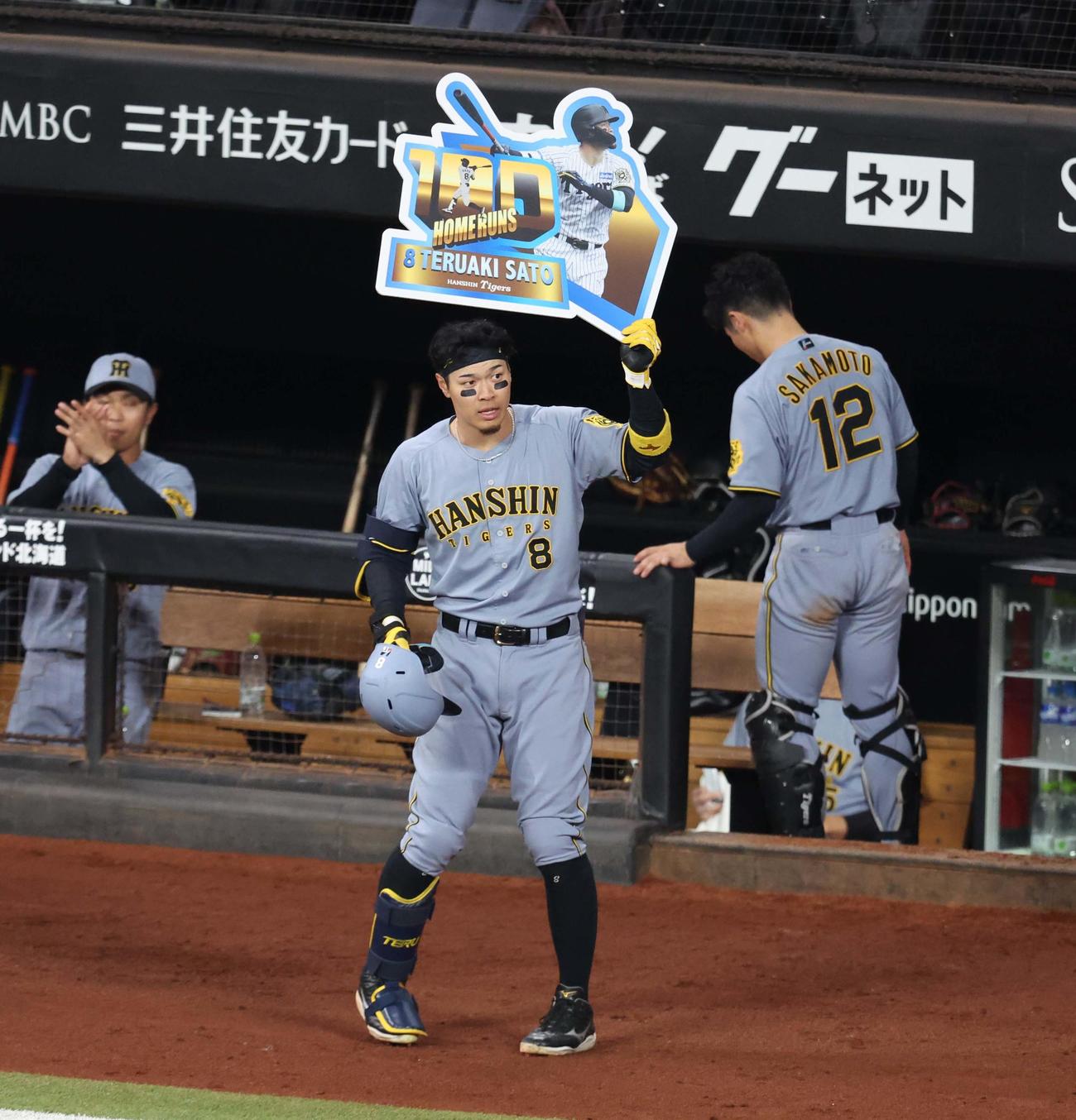 日本ハム対阪神　8回表阪神無死、右越えに通算100本塁打を放ち記念ボードを掲げる佐藤輝（撮影・黒川智章）