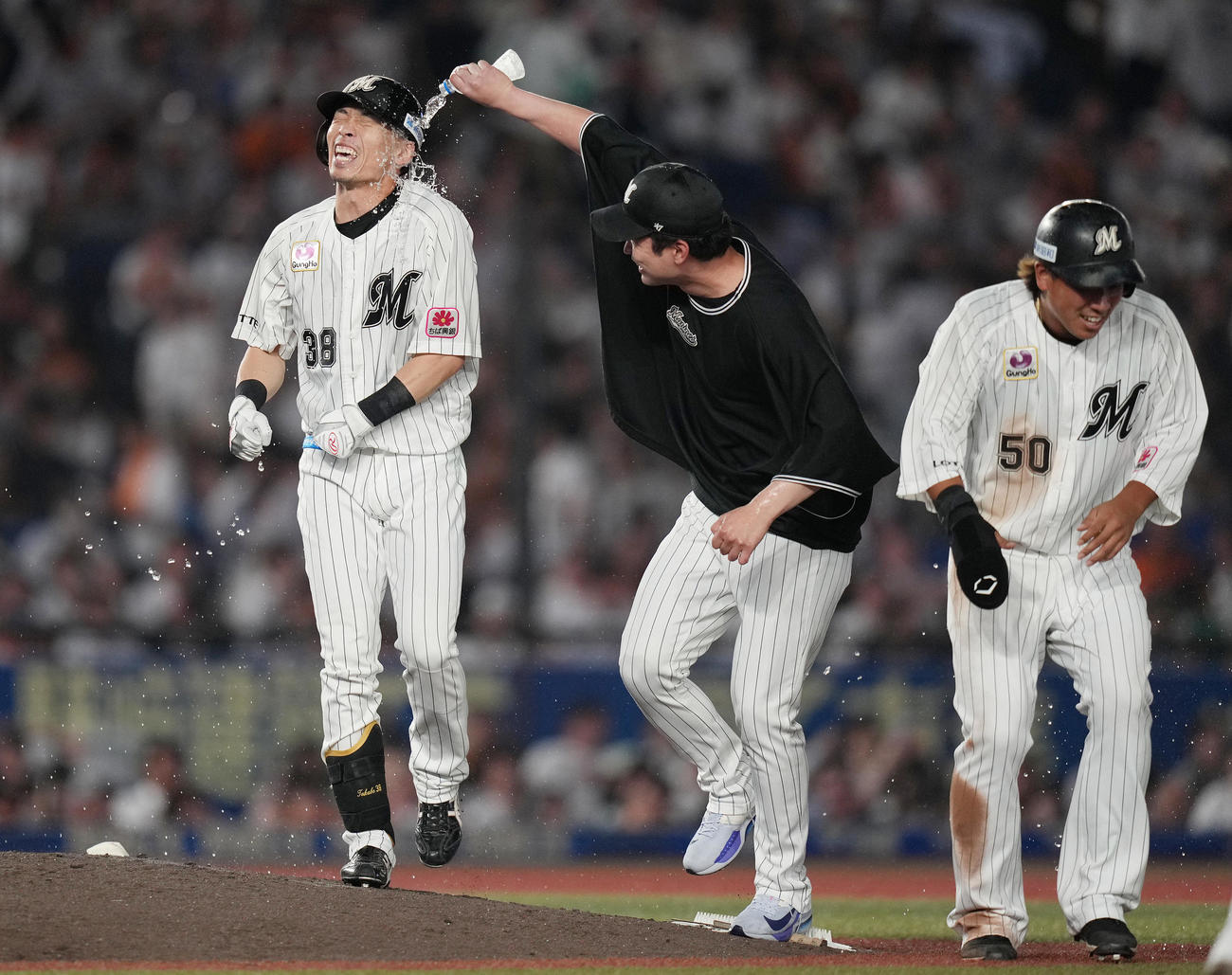 ロッテ対巨人　10回裏ロッテ2死満塁、押し出し死球を受けサヨナラ勝ちした高部（左）は種市（中央）から水をかけられる（撮影・鈴木みどり）