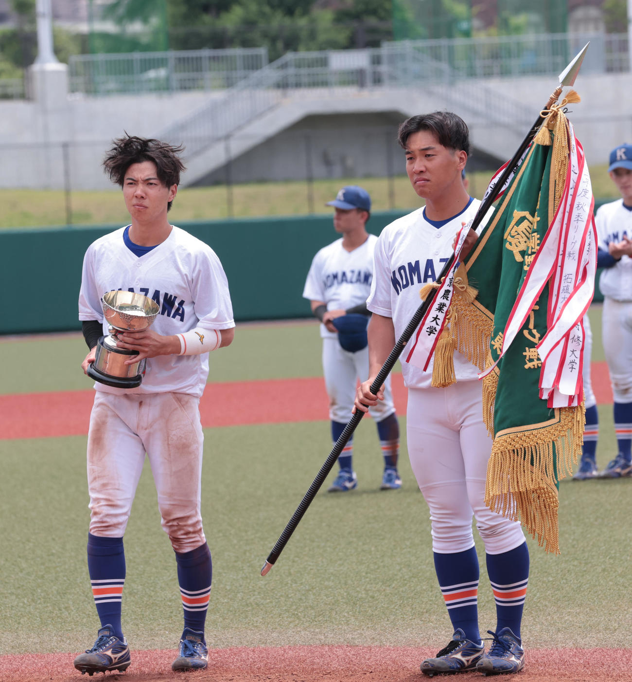 東都大学2部優勝決定戦を制した駒大・出村主将（右）は優勝旗を受け取る、左は優勝杯を持つ小林＝2025年6月6日（撮影・柴田隆二）
