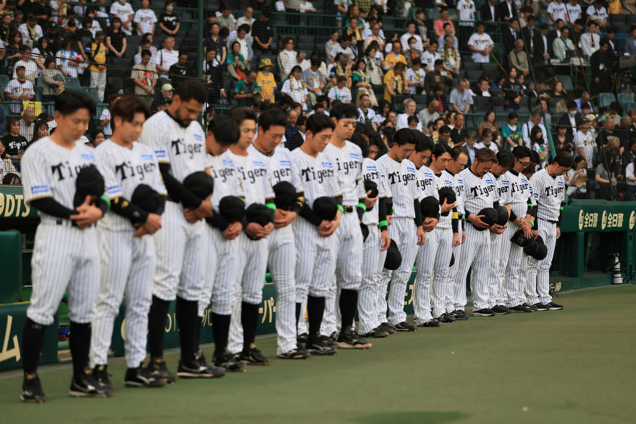 阪神対オリックス　亡くなった長嶋茂雄巨人終身名誉監督に向け、半旗が掲げられた甲子園球場で黙とうする阪神ナイン（撮影・宮崎幸一）