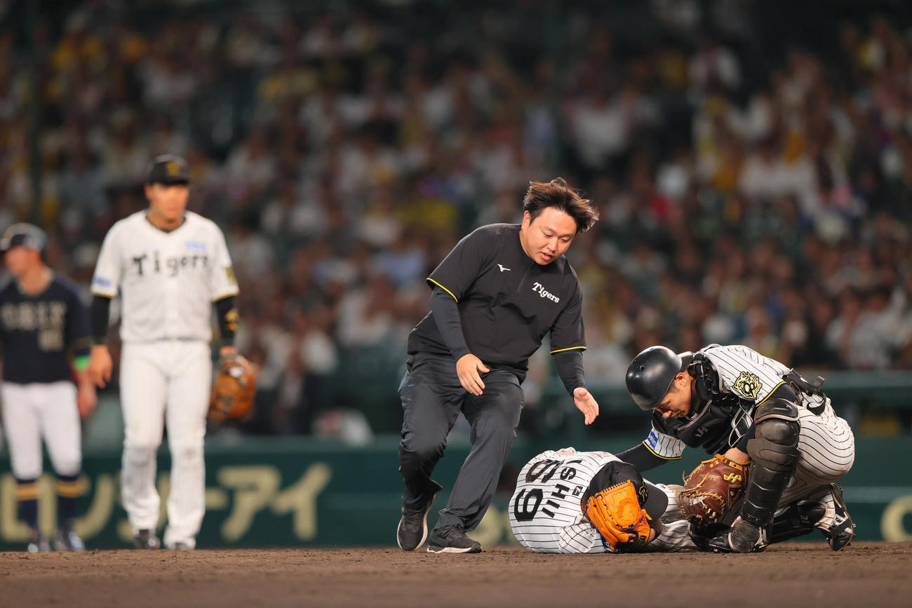 阪神対オリックス　9回表オリックス無死、捕手坂本（右）は広岡の打球が頭部に当たった石井の元に駆けつける（撮影・上山淳一）