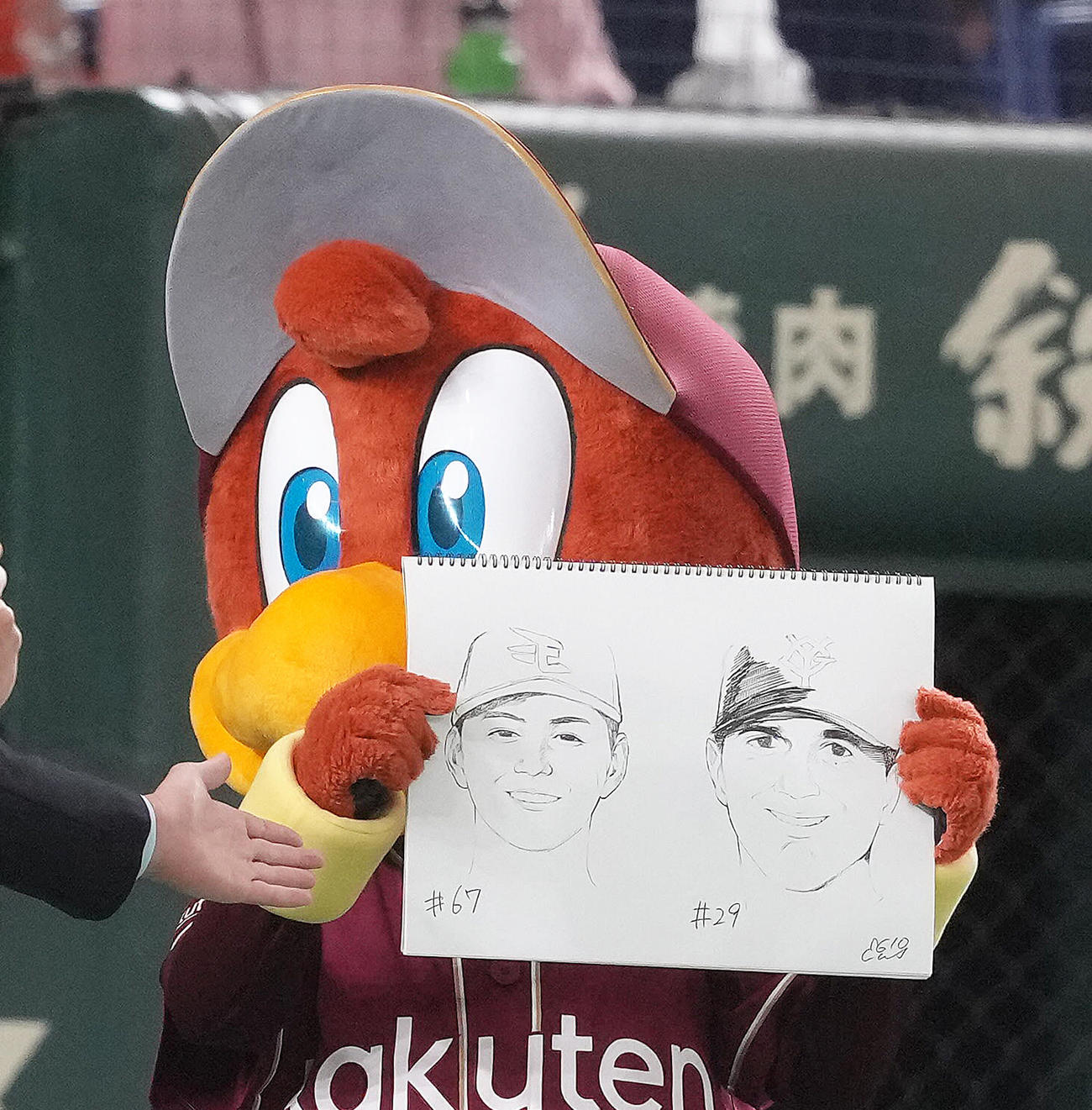 東京ドームに来場し、両チームの先発楽天大内（左）と巨人グリフィンの似顔絵を披露する楽天のマスコットのクラッチ（撮影・足立雅史）