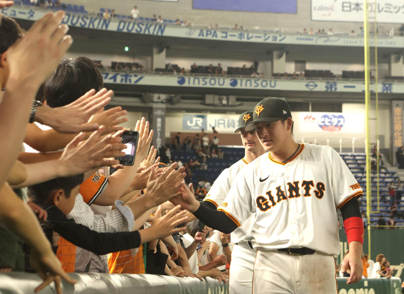 巨人対楽天　勝利を飾りファンとハイタッチする増田陸。後方はグリフィン（撮影・水谷安孝）