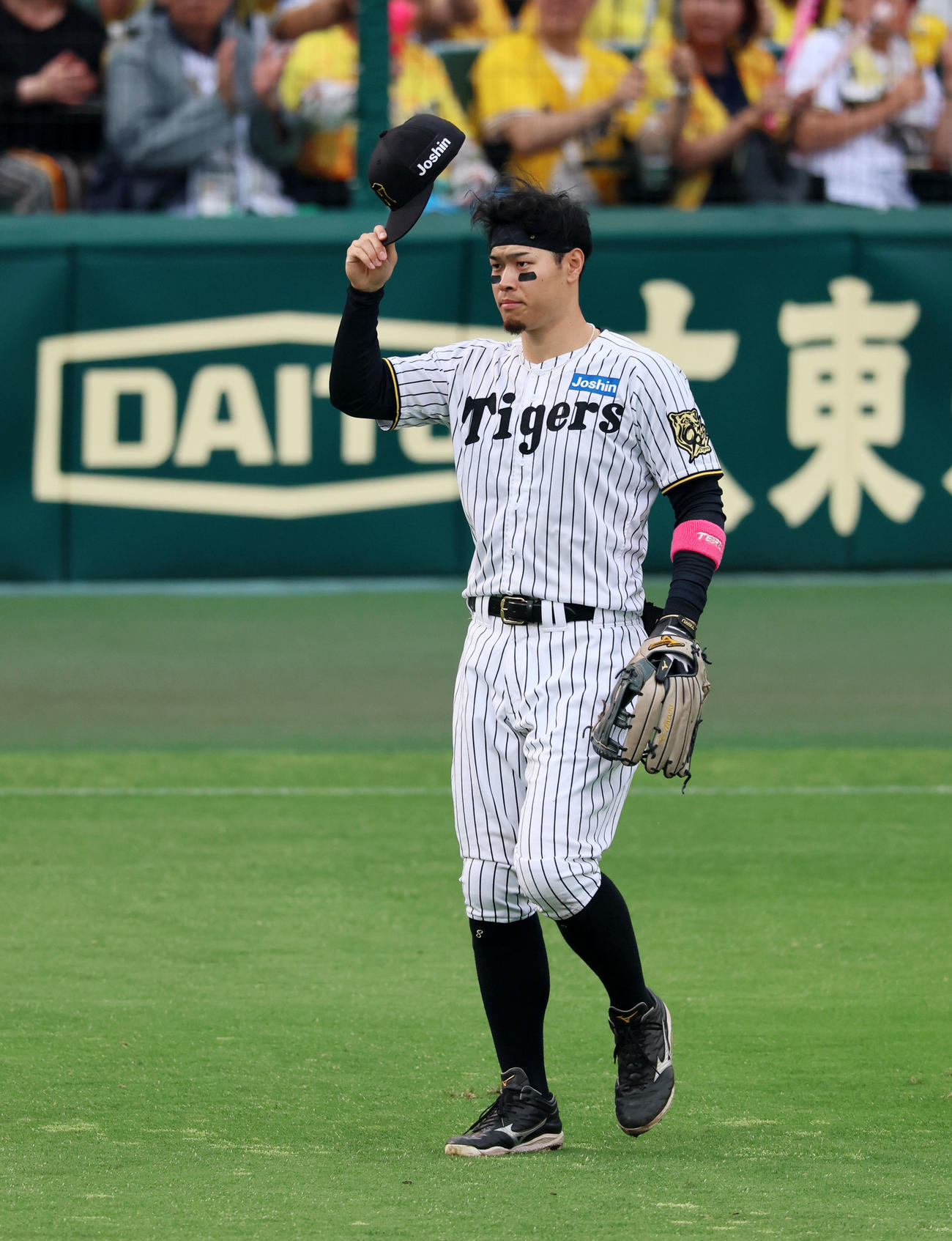 阪神対オリックス　8回裏に満塁弾を放った佐藤輝は攻守交代で守備位置に就きスタンドのファンに帽子を取ってあいさつする（撮影・加藤哉）