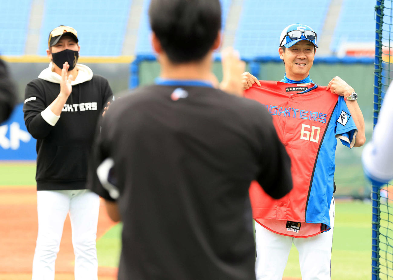 DeNA対日本ハム　試合前、この日60歳を迎えた日本ハム八木打撃コーチ（右）は赤いユニホームを贈られ笑顔。左は新庄監督（撮影・浅見桂子）