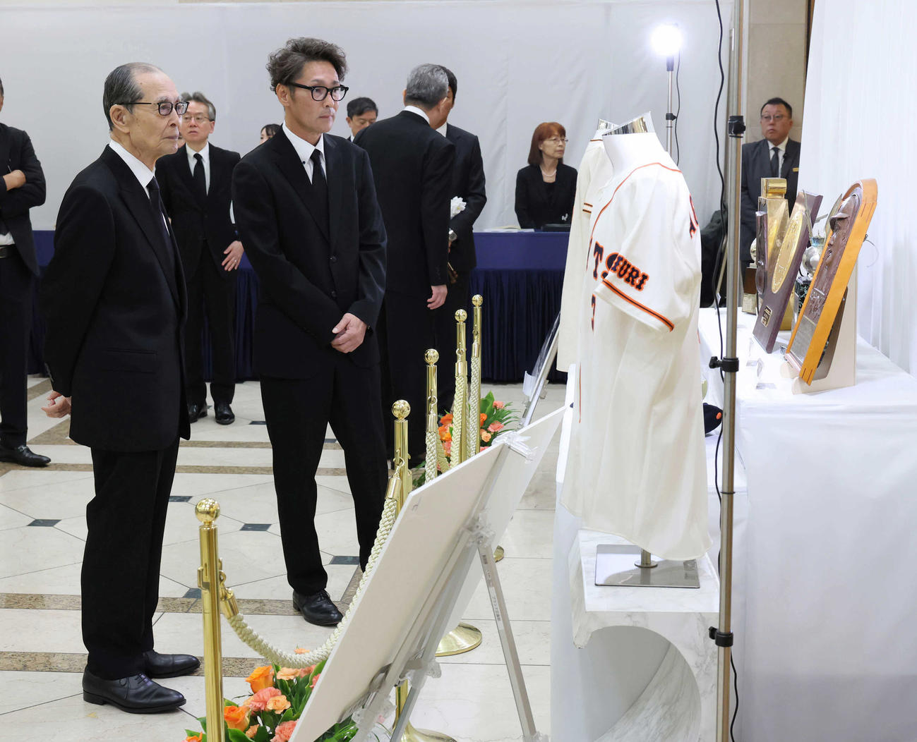 通夜・告別式の会場に展示されたゆかりの品を見る巨人OBの王さん（左）と元木さん（読売新聞社提供）