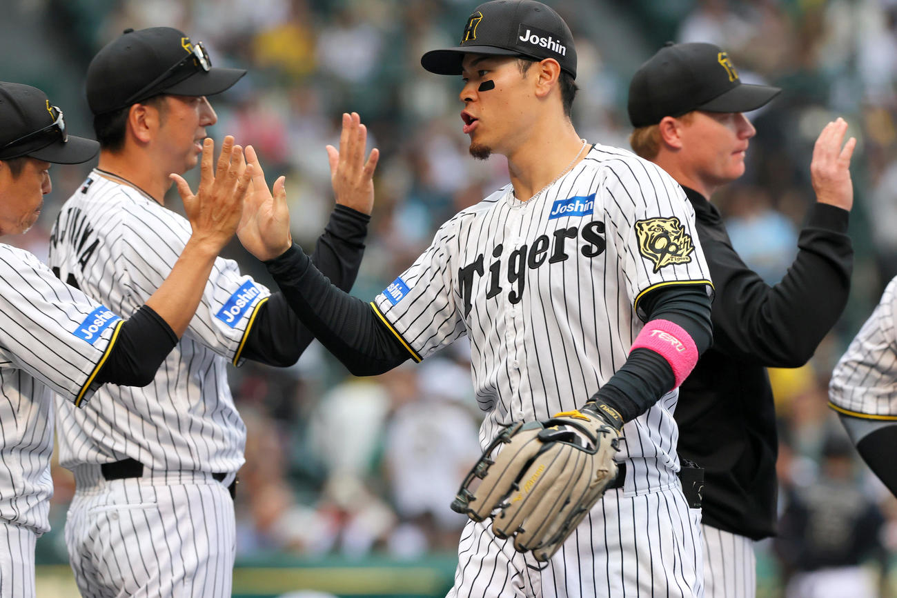 阪神対オリックス　オリックスに勝利した藤川監督（左から2人目）はベンチ前で佐藤輝明（手前）らとタッチをかわす（撮影・上山淳一）