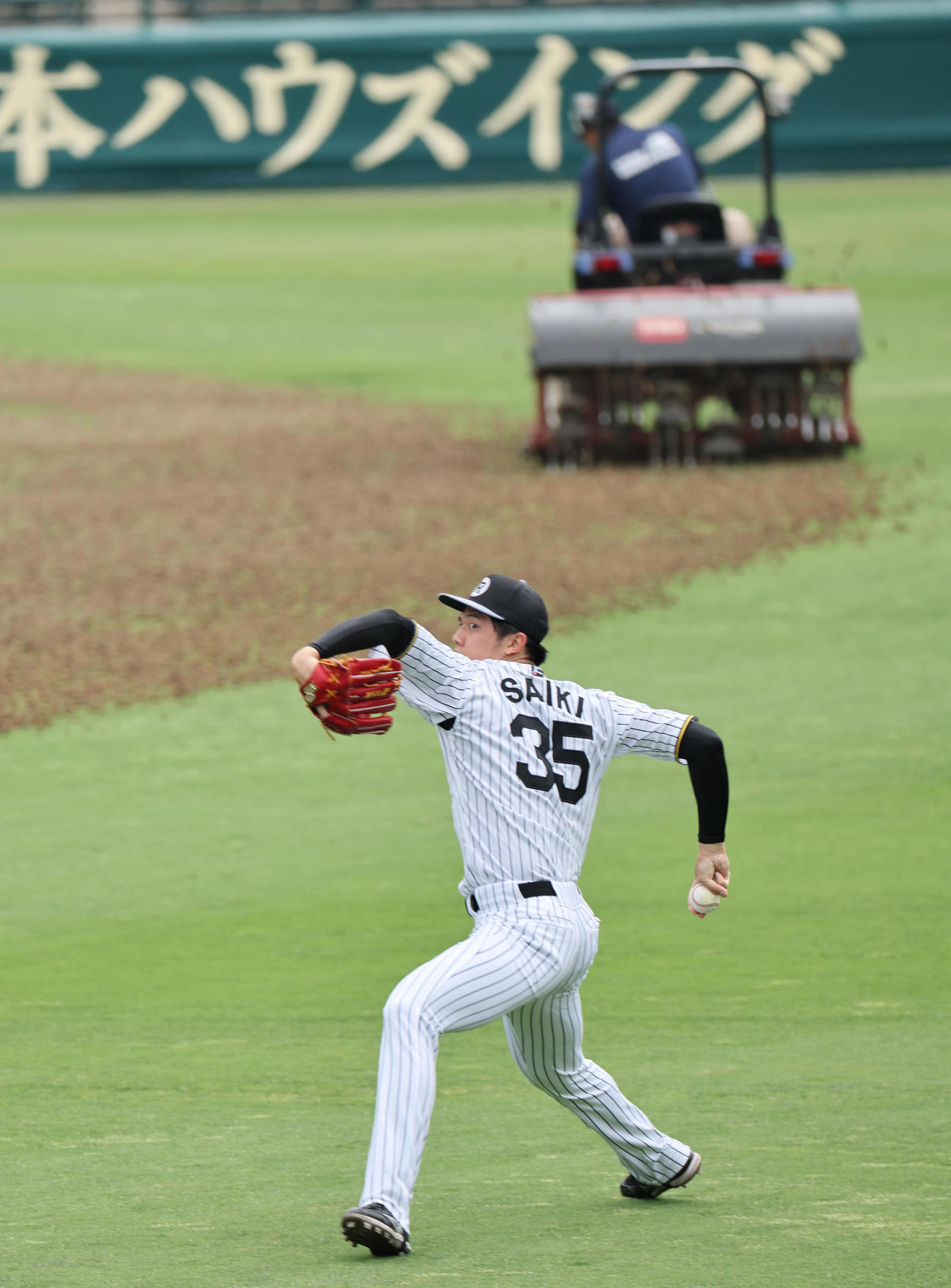 芝のメンテナンスがおこなれている横でキャッチボールする阪神才木（撮影・西尾就之）