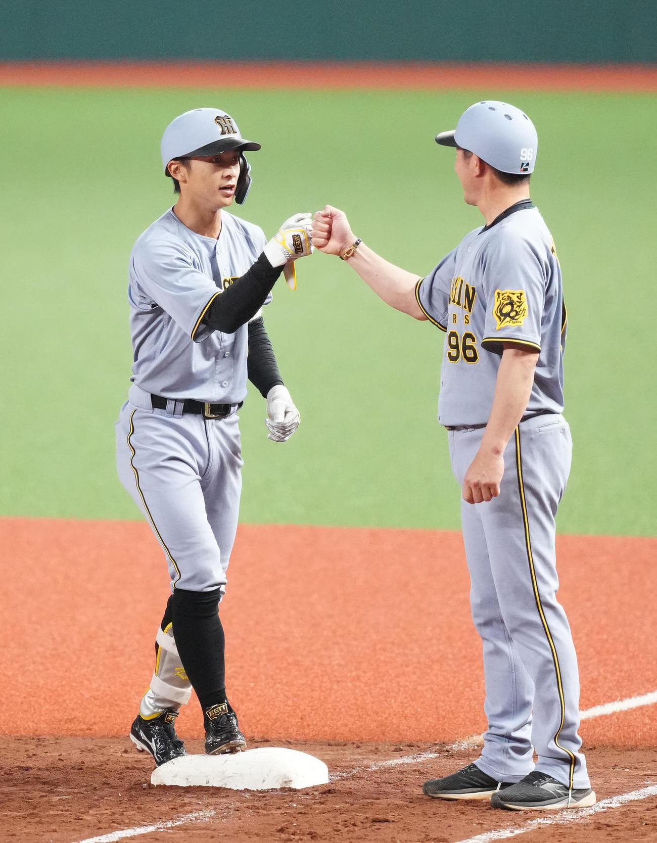 西武対阪神　2回表阪神2死一、三塁、先制適時打を放ち、筒井一塁ベースコーチ（右）とタッチを交わす熊谷（撮影・江口和貴）