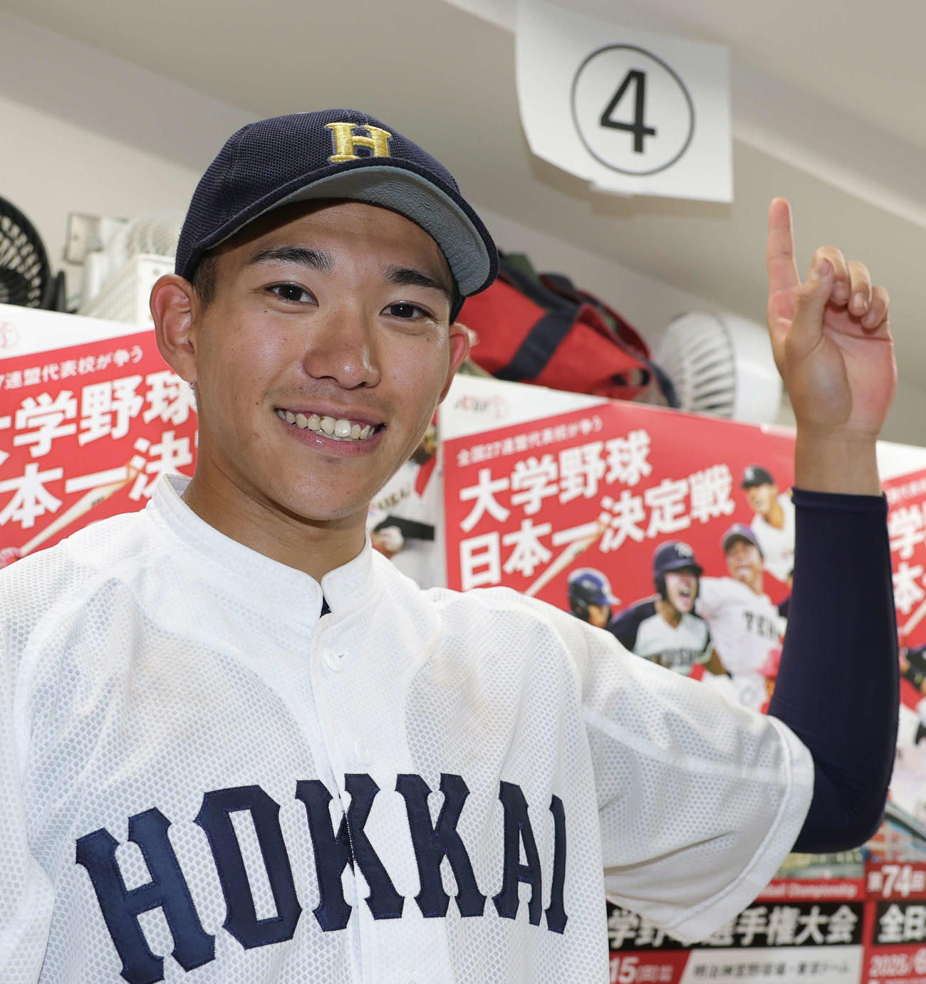 佛教大対北海学園大　4安打と大活躍の北海学園大・下向は、試合後のインタビューの位置が4番にあたり、笑顔で指をさす（撮影・野上伸悟）