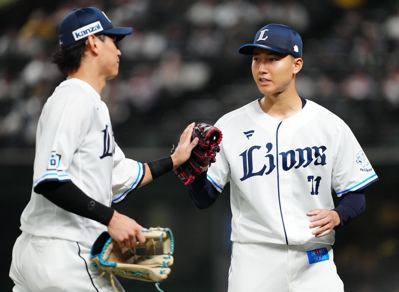 西武対阪神　3回表終了後、西武中堅手西川（左）とタッチを交わす先発の菅井（撮影・江口和貴）