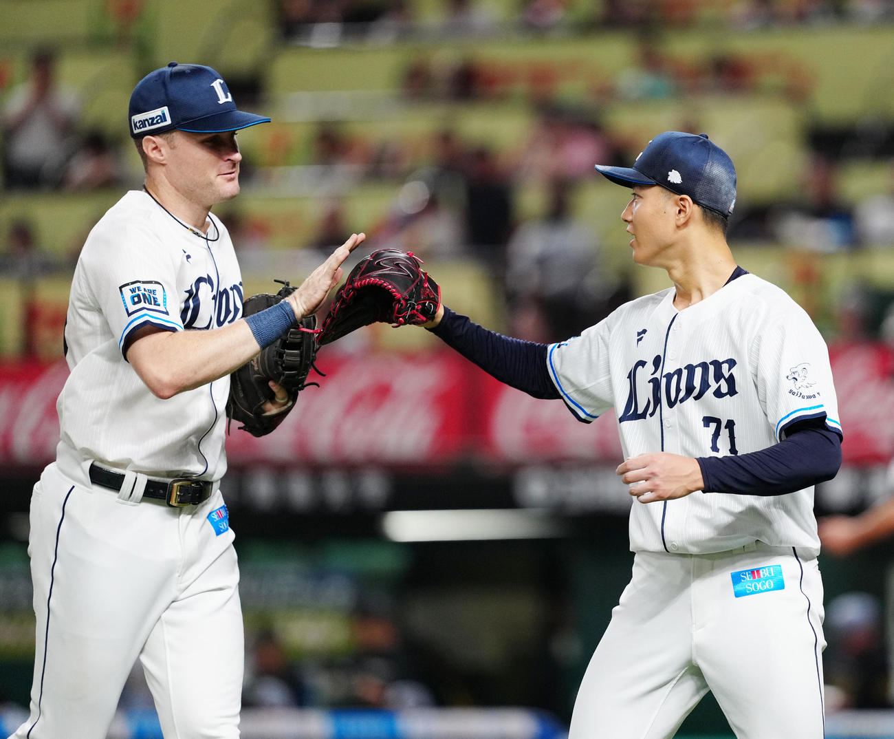 西武対阪神　4回表終了後、西武一塁手ネビン（左）とタッチを交わす先発の菅井（撮影・江口和貴）