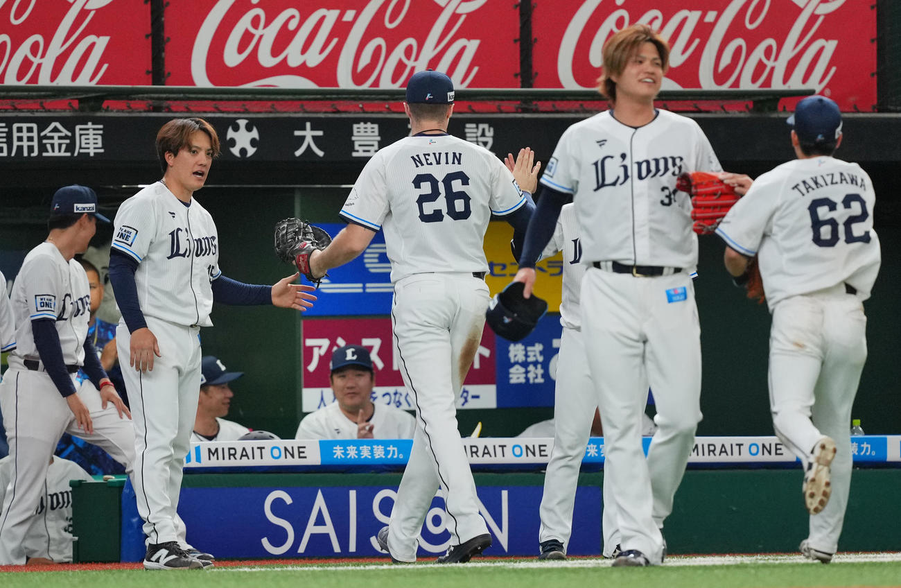 西武対中日　7回表中日の攻撃を無失点に抑えた西武与座（左から2人目）と甲斐野（同4人目）は笑顔でナインとタッチを交わす（撮影・垰建太）