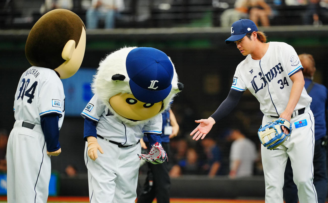 西武対中日　セレモニアルピッチを終えたクレヨンしんちゃんの野原しんのすけ（中央）に握手を求めるもボールを落としてしまいタイミングが合わない西武甲斐野（右）（撮影・垰建太）