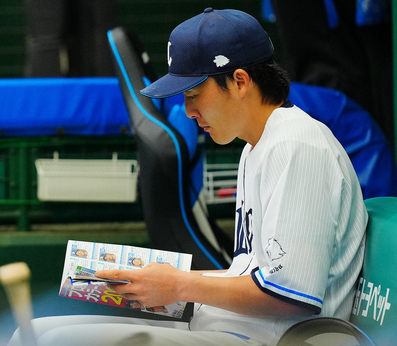 西武対中日　試合前、スタメンを外れた西武源田はベンチで選手名鑑を読み込む（撮影・垰建太）