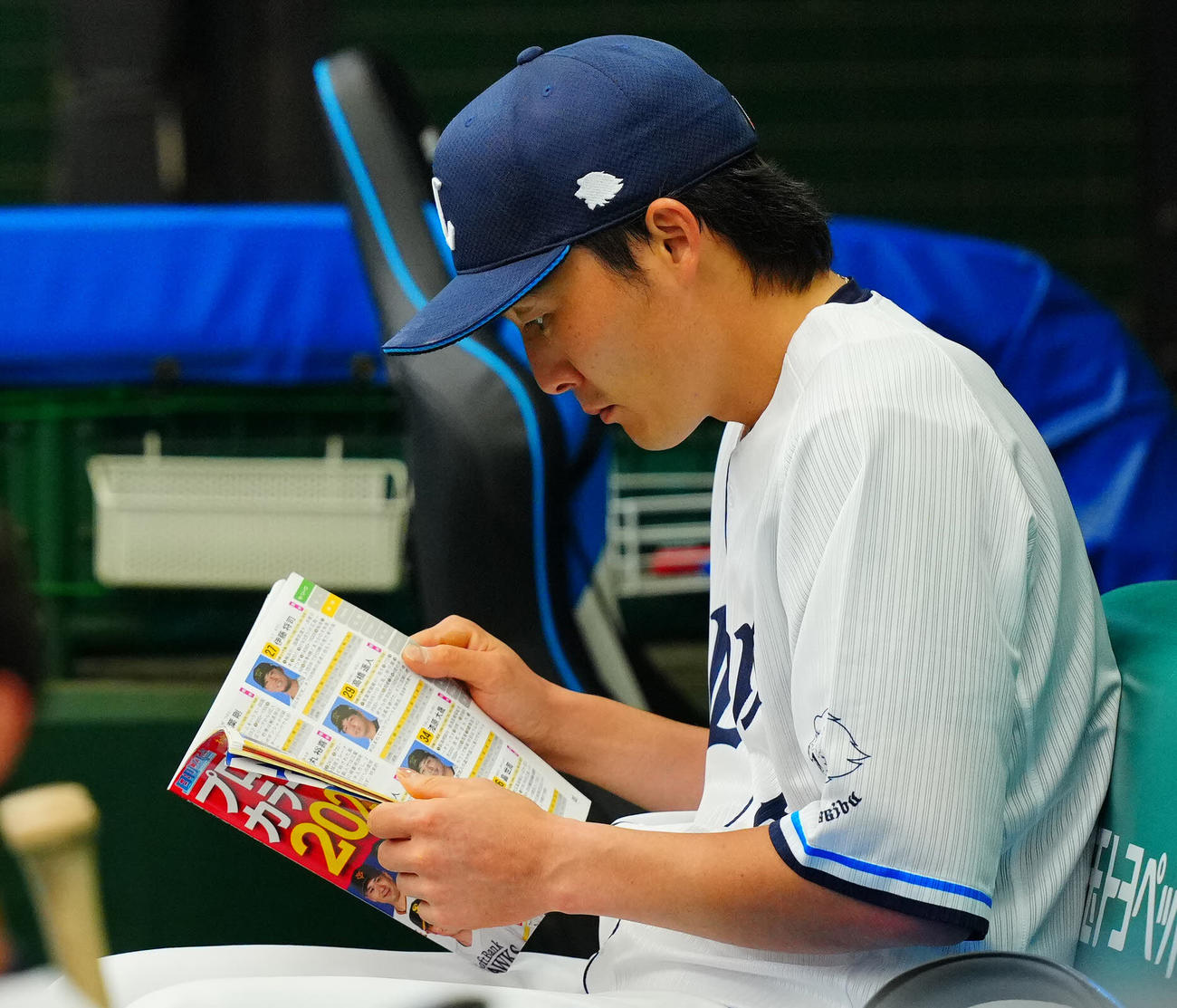 西武対中日　試合前、スタメンを外れた西武源田はベンチで選手名鑑を読み込む（撮影・垰建太）