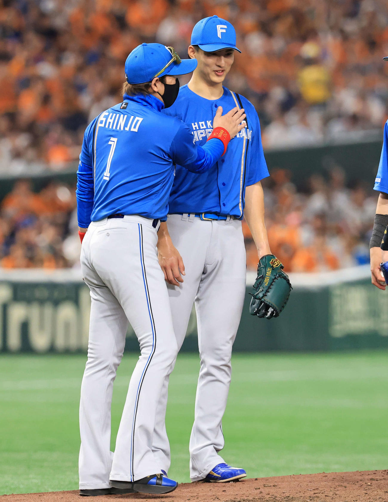 巨人対日本ハム　7回裏巨人2死一、二塁の場面で降板を告げられた達（右）は新庄監督から胸をたたかれ労われる（撮影・浅見桂子）