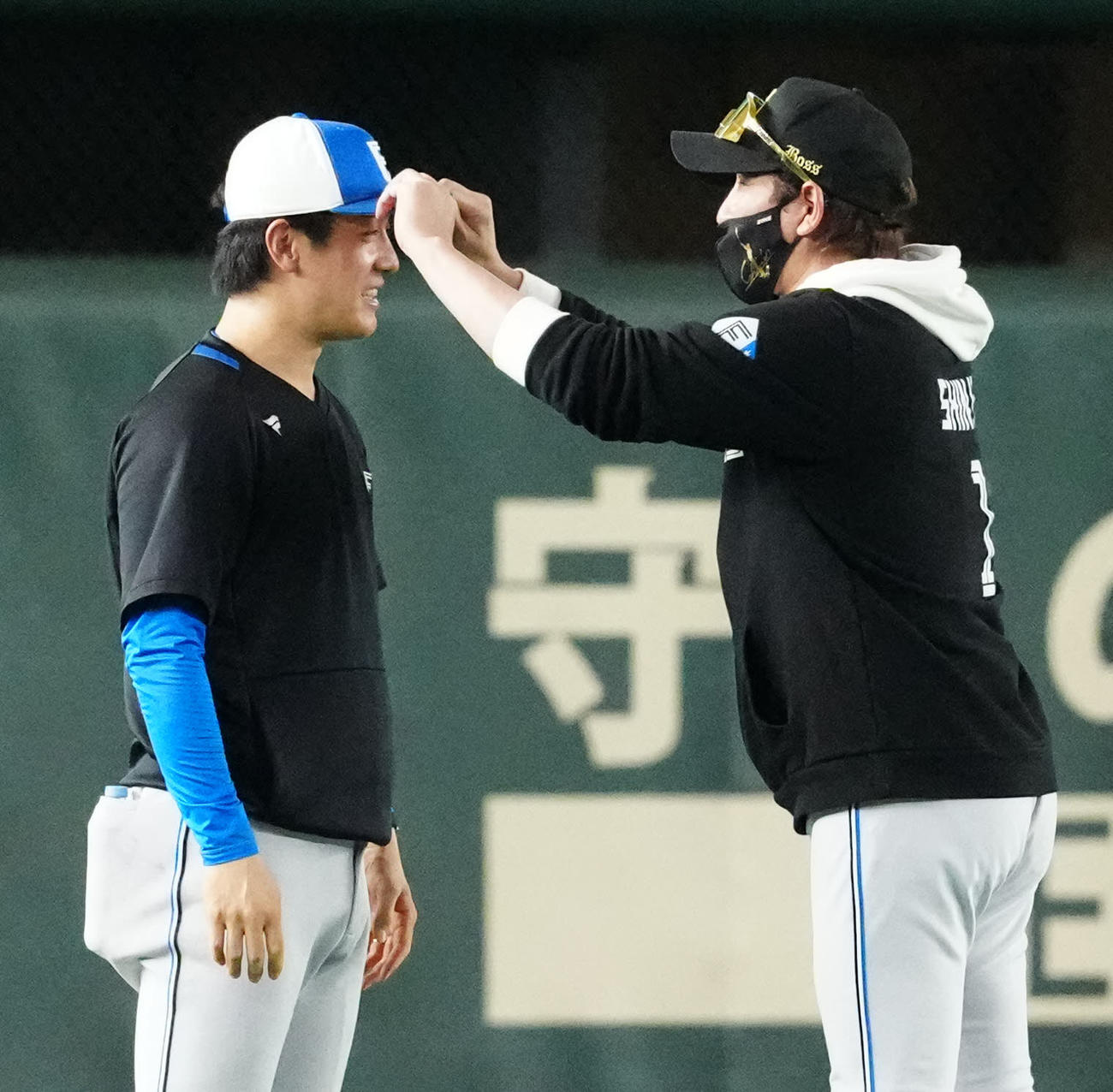 巨人対日本ハム　試合前練習を終え引き揚げる日本ハム北山（左）の帽子のつばを曲げ調整する新庄監督（撮影・江口和貴）