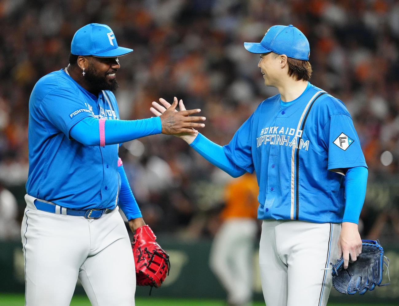 巨人対日本ハム　4回裏終了後、タッチを交わす日本ハム山崎（右）とレイエス（撮影・江口和貴）