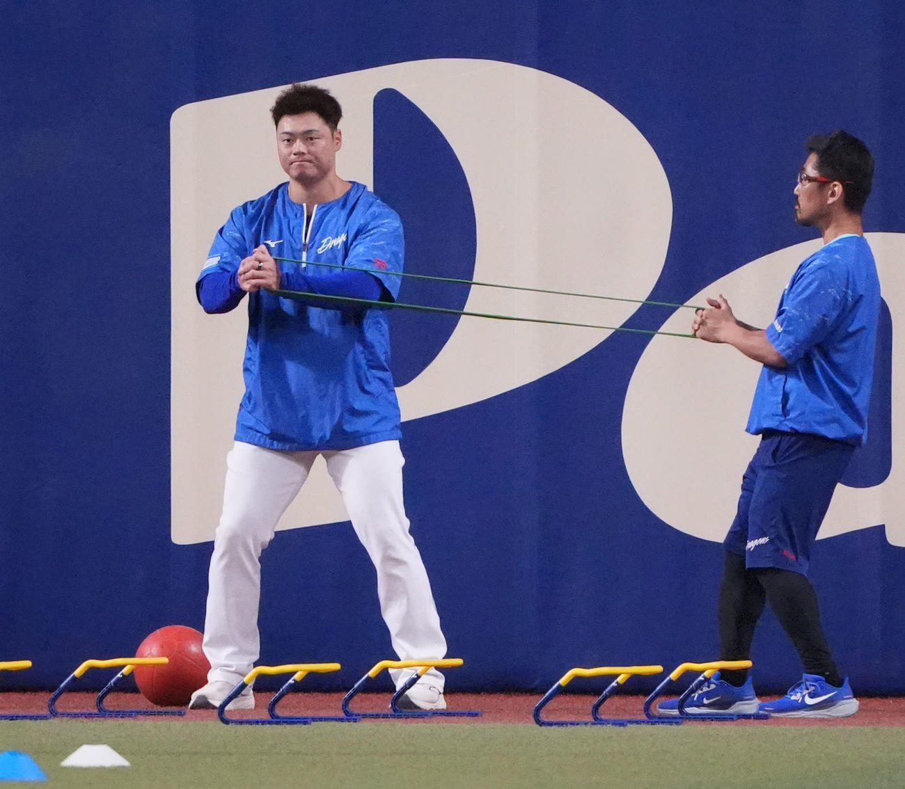 中日対オリックス　試合前、細川（左）はチューブを利用しトレーニングをする（撮影・森本幸一）
