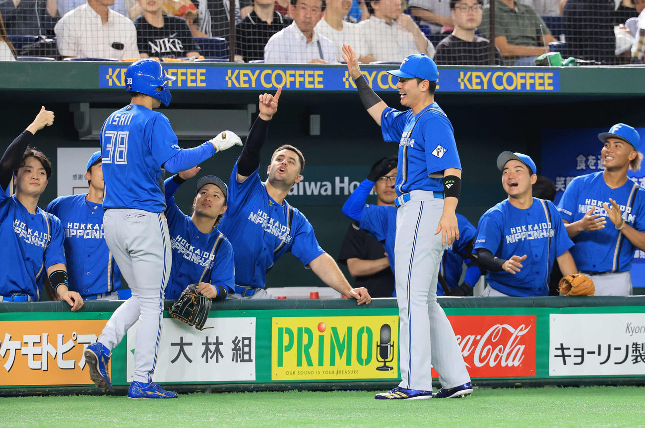 巨人対日本ハム　2回表日本ハム2死一塁、上川畑の適時二塁打で一気に本塁生還した石井（左）を笑顔で迎える清宮幸（右手前）ら選手たち（撮影・浅見桂子）