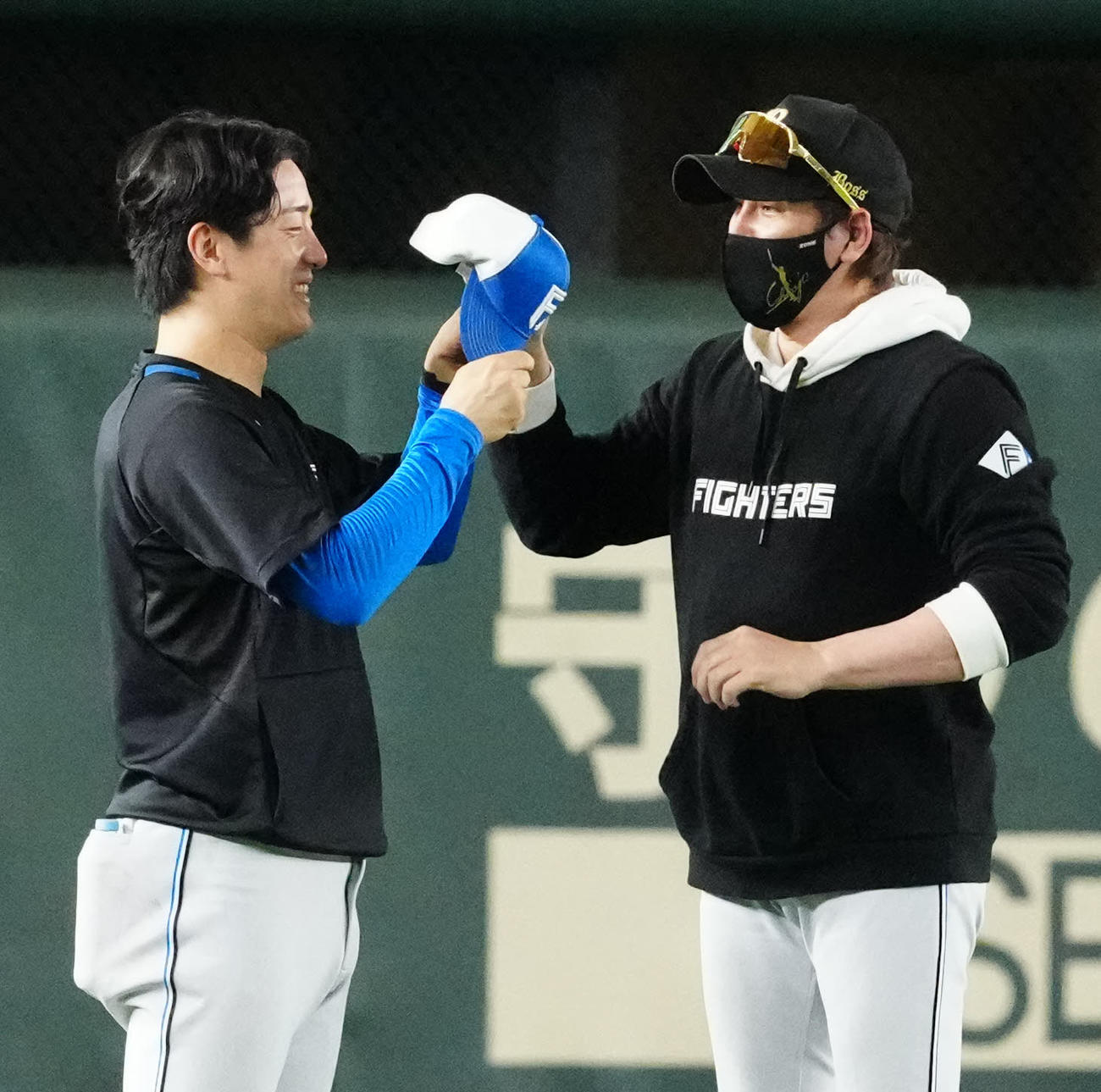 巨人対日本ハム　試合前練習を終え引き揚げる日本ハム北山（左）の帽子のつばを曲げて渡す新庄監督（撮影・江口和貴）