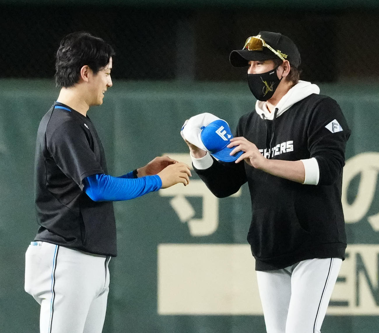 巨人対日本ハム　試合前練習を終え引き揚げる日本ハム北山（左）の帽子のつばを曲げて渡す新庄監督（撮影・江口和貴）