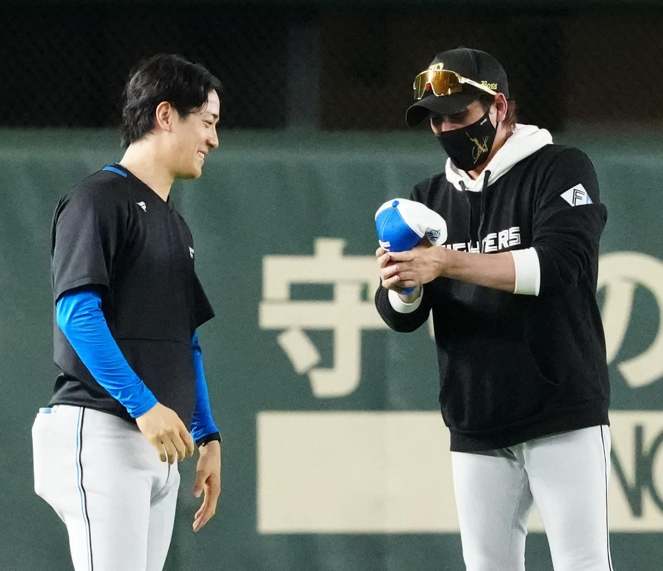 巨人対日本ハム　試合前練習を終え引き揚げる日本ハム北山（左）の帽子のつばを曲げる新庄監督（撮影・江口和貴）