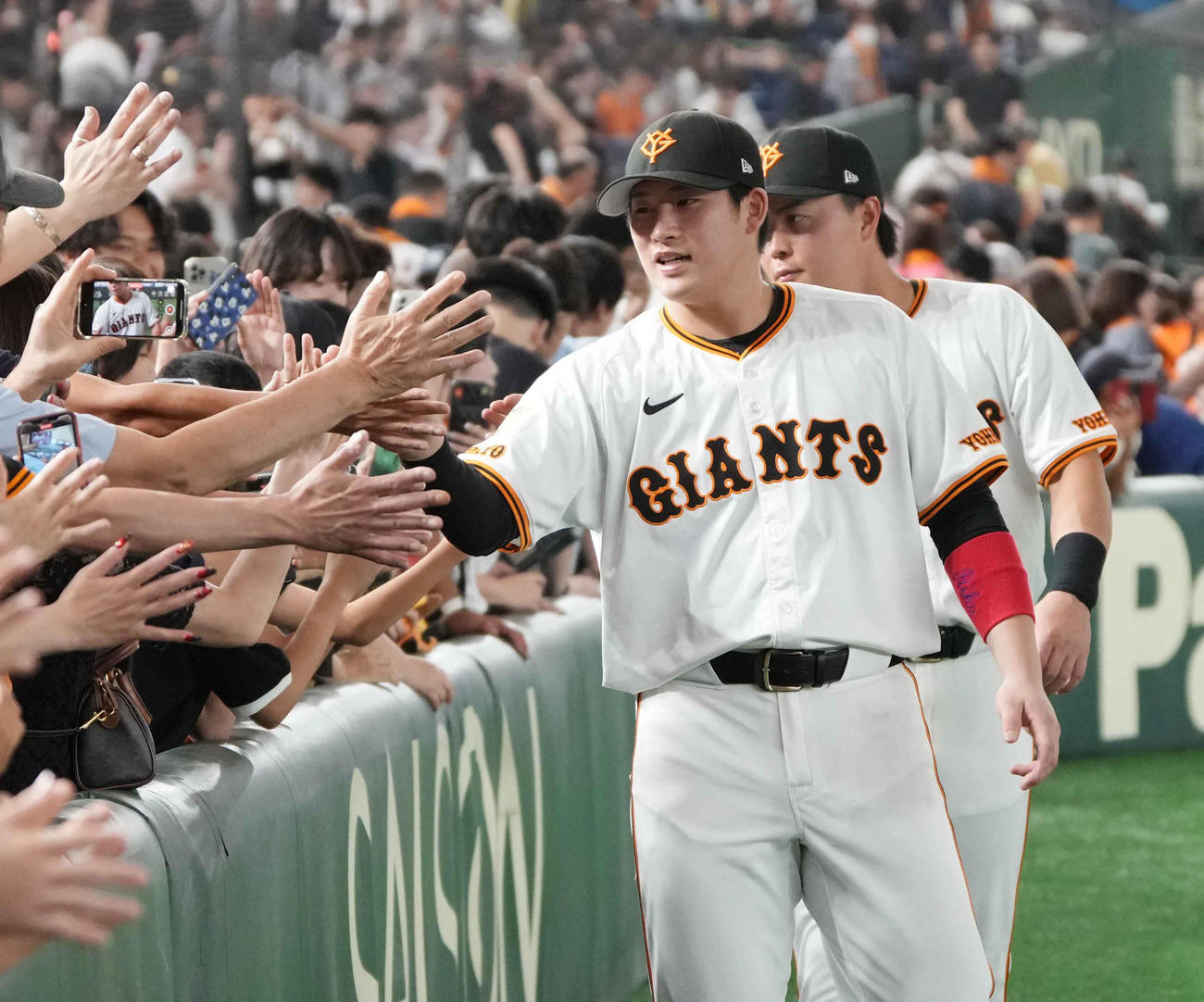 巨人対西武　ファンとハイタッチする巨人増田陸。後方は岡田（撮影・小沢裕）