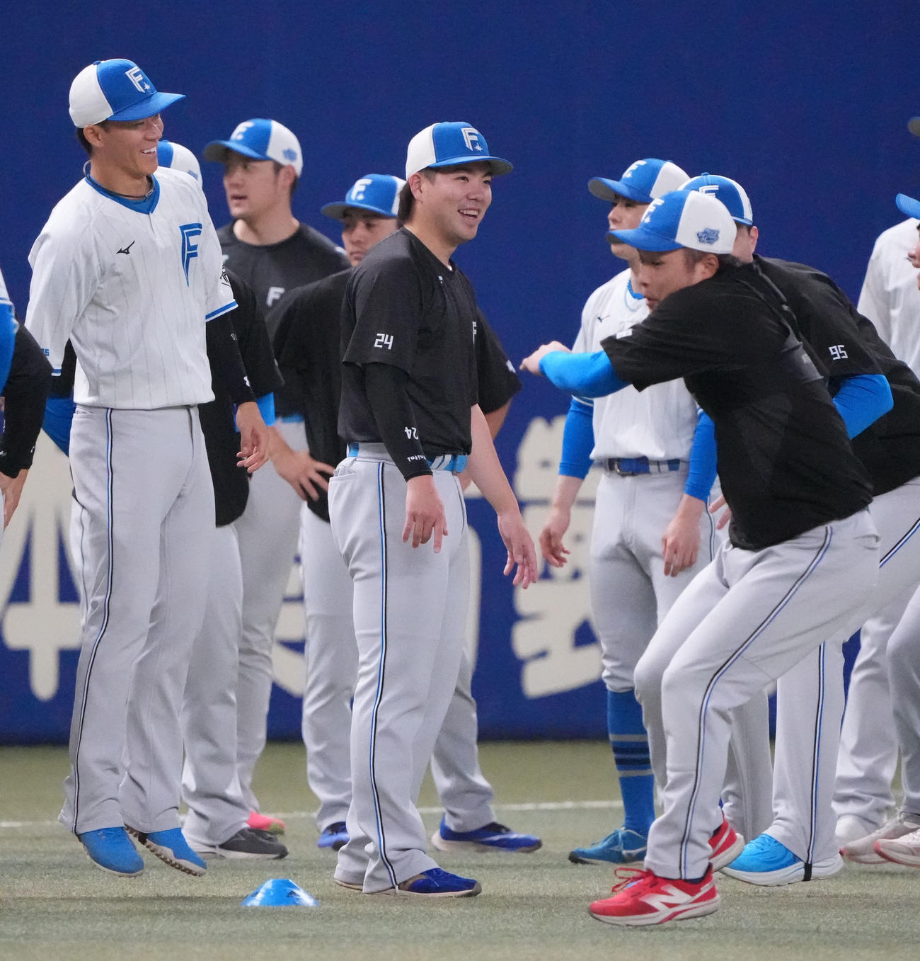 中日対日本ハム　試合前、明るい表情で体をほぐす金村（中央）ら日本ハムナイン（撮影・森本幸一）
