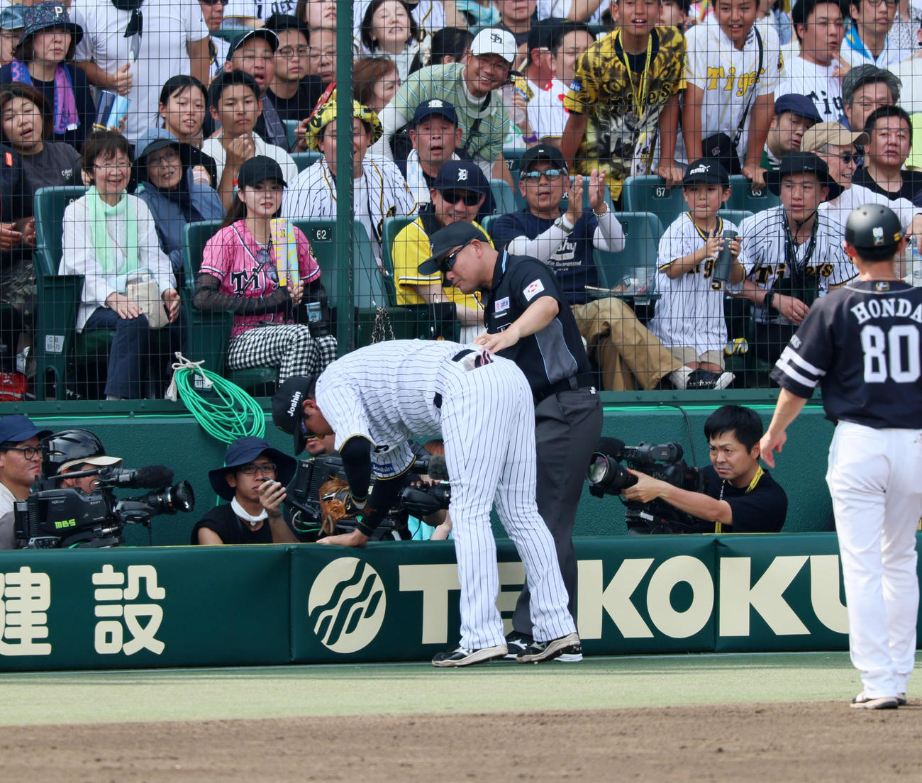 阪神対ソフトバンク　3回表ソフトバンク2死、野村勇の邪飛を追って一塁側カメラマン席に転落した大山のベルトを持って起き上がらせる福家一塁塁審（撮影・加藤哉）