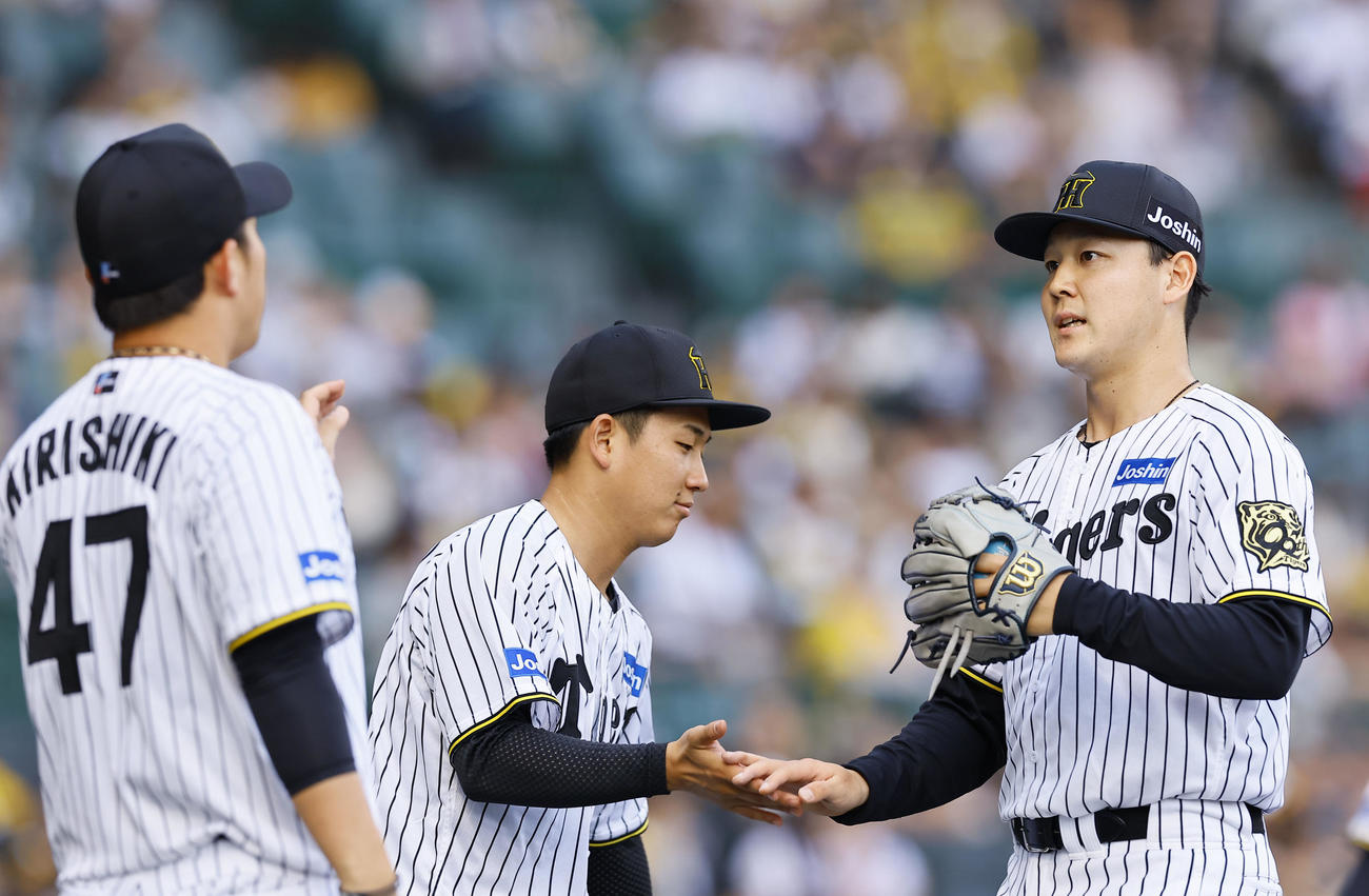 阪神対ソフトバンク　9回を終え、伊原らに出迎えられベンチに戻る阪神木下（右）（撮影・藤尾明華）