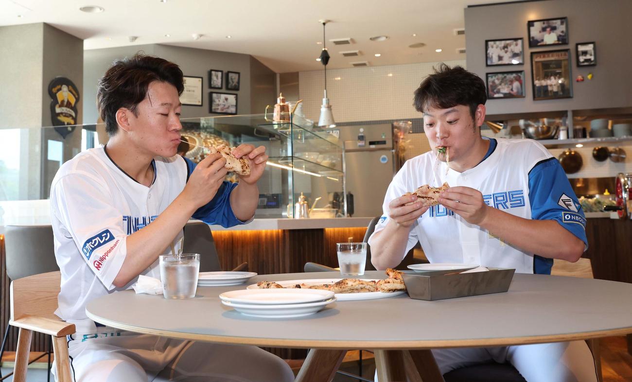 Fビレッジ内にオープンする商業施設でピザを食べる日本ハム矢沢（左）と斎藤（撮影・黒川智章）