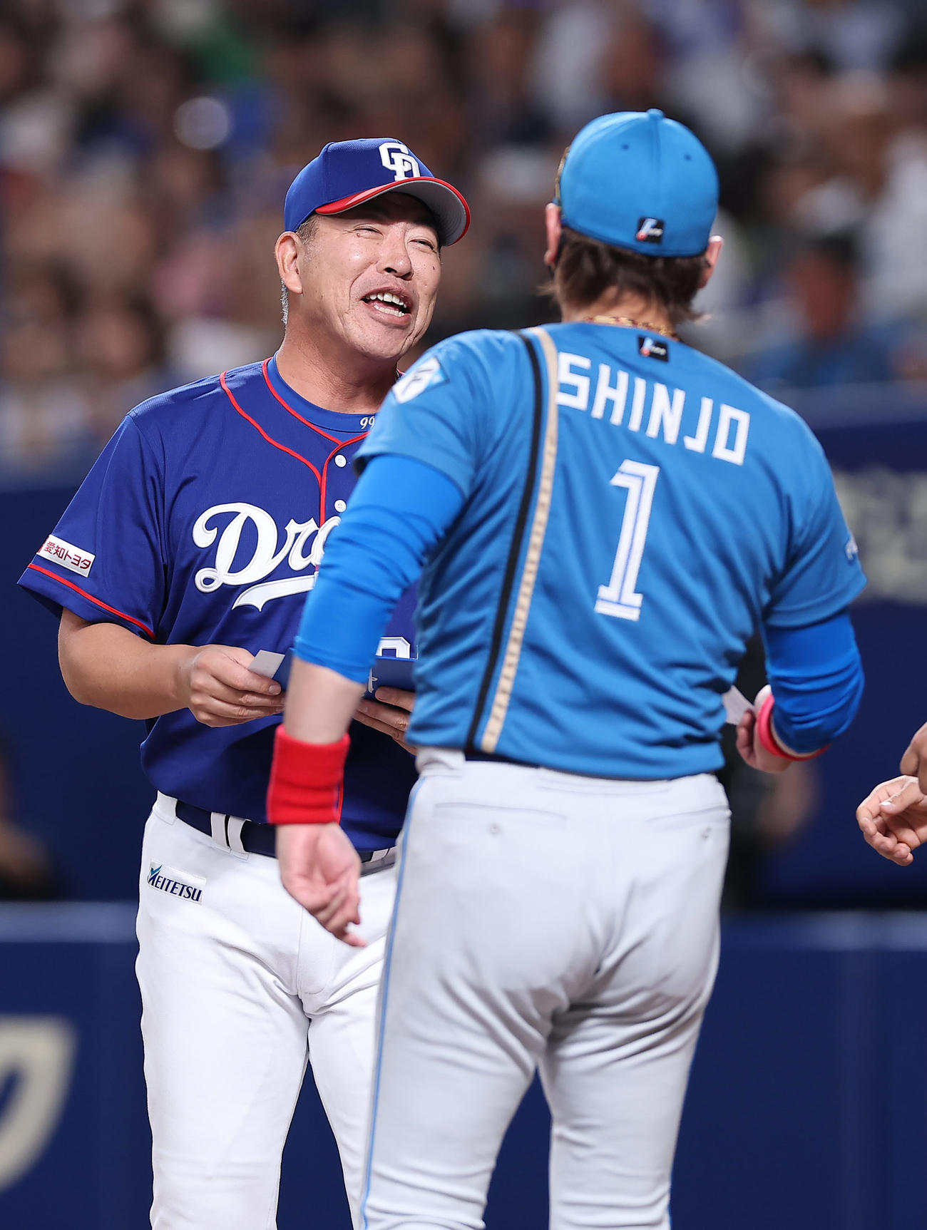 中日対日本ハム　日本ハム新庄監督（手前）と笑顔でメンバー表交換を行う中日井上監督（2025年6月22日撮影）