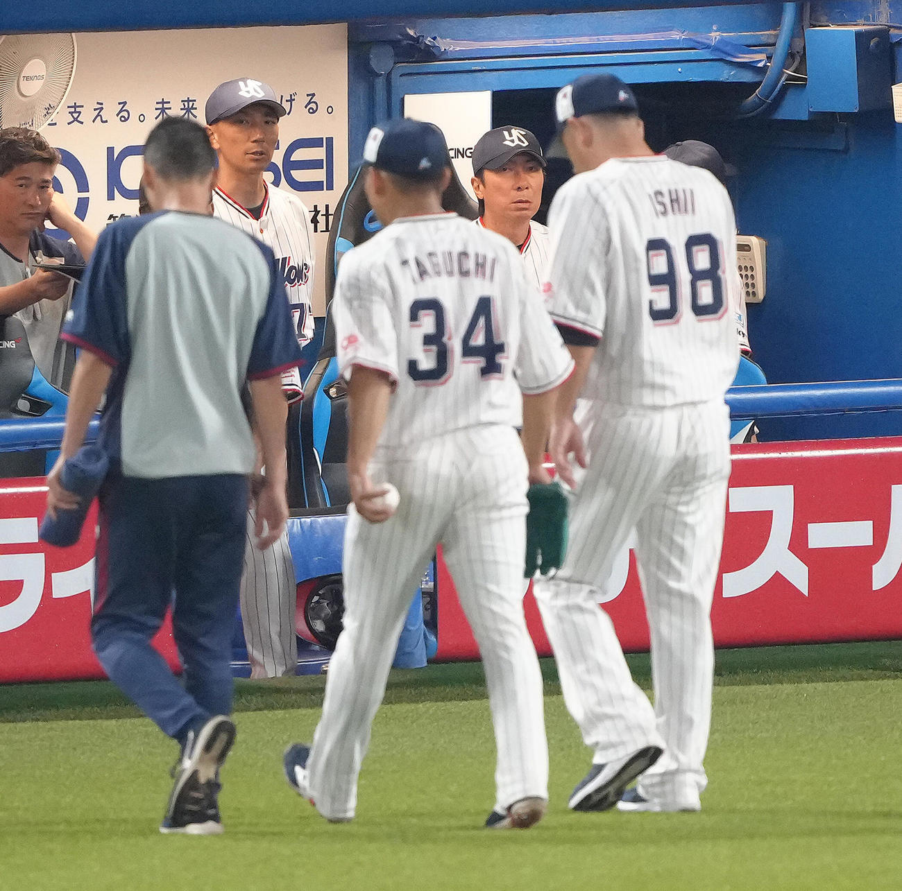 ヤクルト対阪神　7回途中、治療のためベンチに戻るヤクルト田口（手前中央）を厳しい表情で見つめる高津監督（後方右）（撮影・足立雅史）
