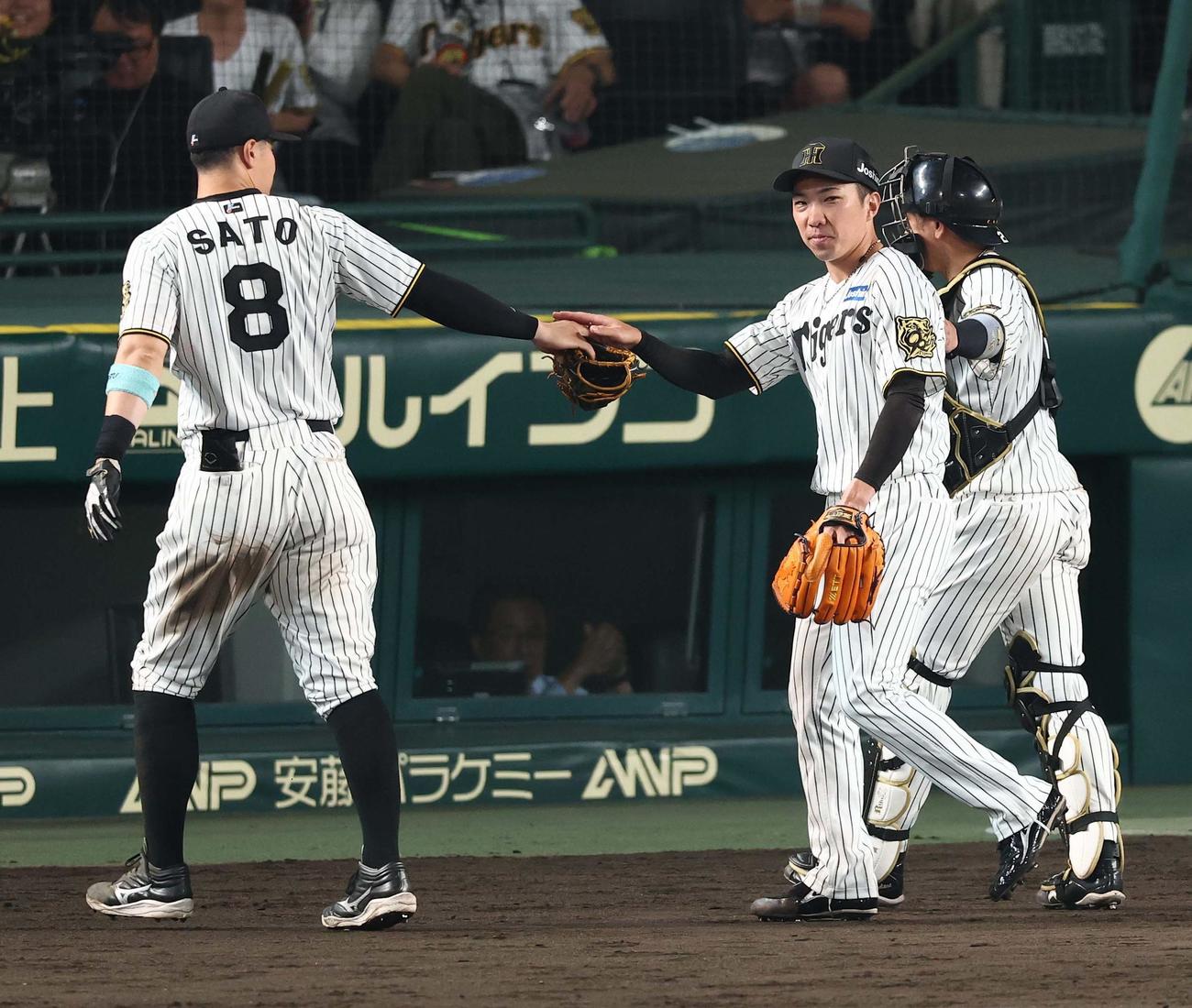 阪神対巨人　8回を無失点に抑えた石井（右）は佐藤輝らナインの出迎えを受ける（撮影・上田博志）