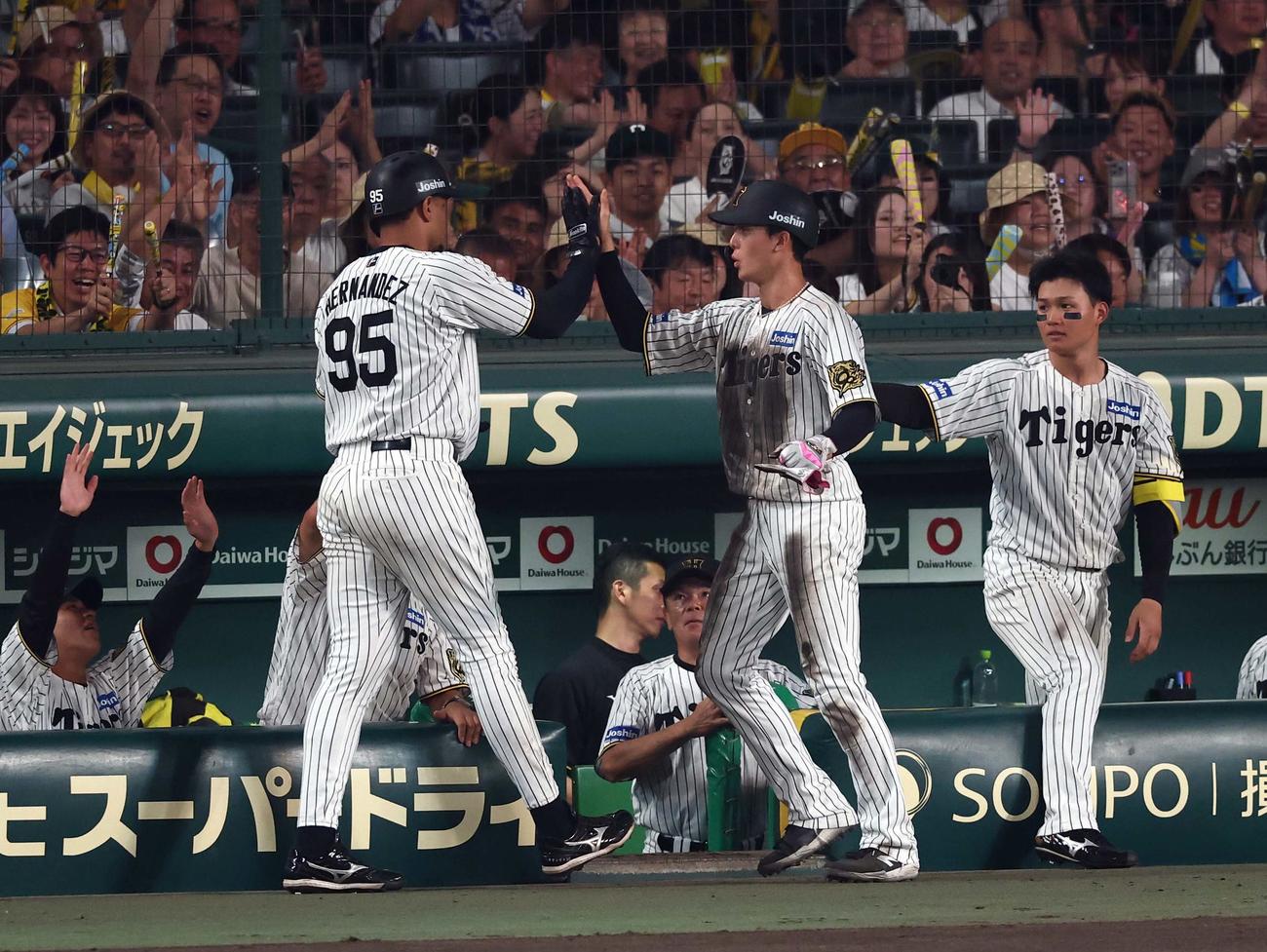 阪神対巨人　5回裏阪神無死一、三塁、生還した小幡（右から2人目）は同点犠飛を放ったヘルナンデスとハイタッチをする（撮影・上田博志）