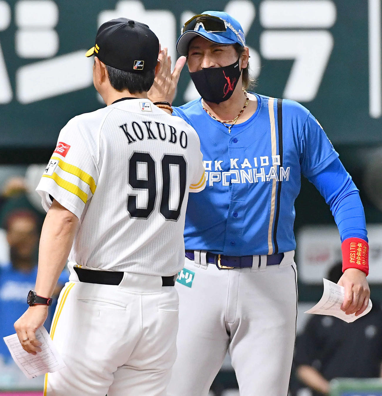 ソフトバンク対日本ハム　試合前、ソフトバンク小久保監督（左）とメンバー表を交換し、笑顔でハイタッチする日本ハム新庄監督（撮影・岩下翔太）