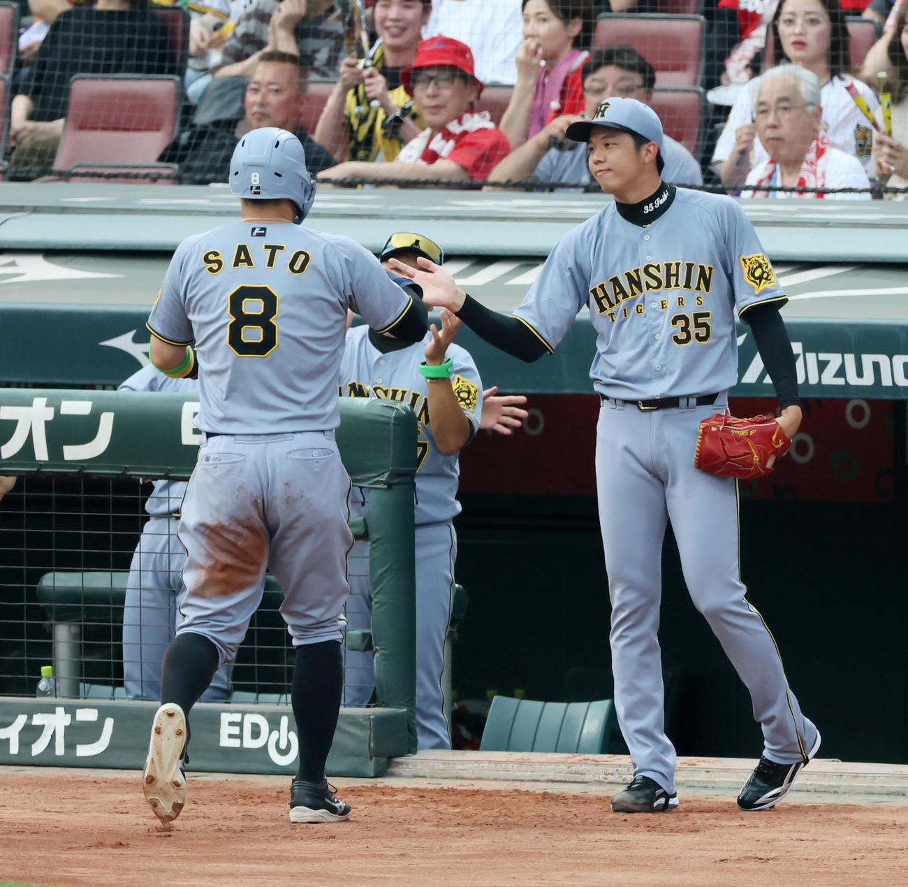 広島対阪神　1回表阪神1死一塁、一塁走者佐藤輝は打者大山のとき二塁盗塁失敗となりベンチ前でキャッチボールする才木がタッチで迎える（撮影・加藤哉）