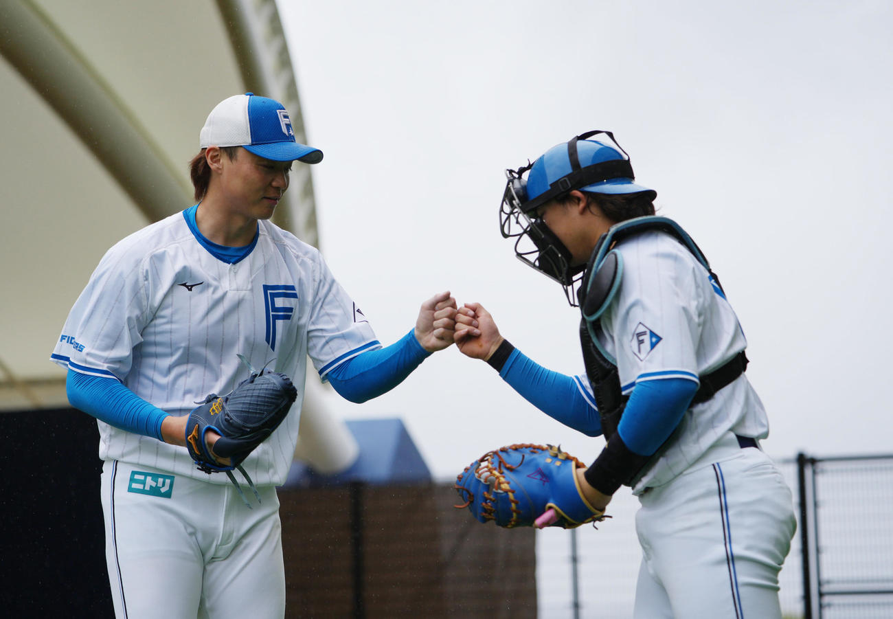 ブルペン投球を終えた日本ハム山崎（左）は田宮とタッチを交わす＝25年2月21日