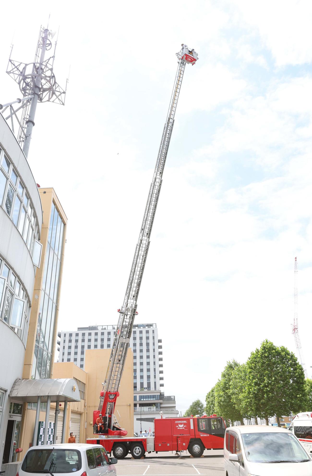 北広島市消防署の1日消防署長に任命されはしご車搭乗体験で地上30メートルまで上がるFビレッジアンバサダー滝谷さん（撮影・黒川智章）