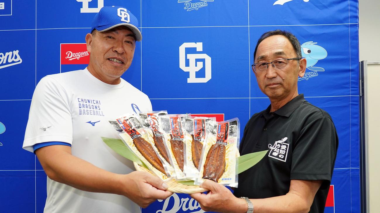 愛知県養鰻漁業者協会の田中三千雄会長（右）から、うなぎの蒲焼きの差し入れを受け取る中日井上監督