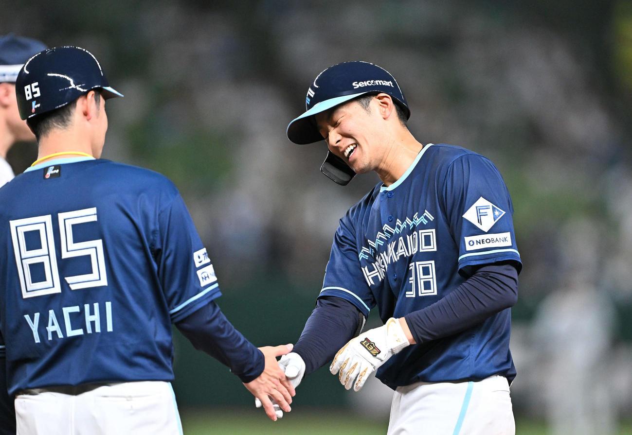 西武対日本ハム　4回表日本ハム2死一塁、右前打を放った石井（右）は谷内コーチとタッチを交わす（撮影・滝沢徹郎）