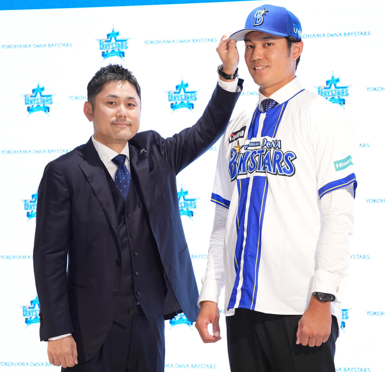 入団会見後、チーム統括本部萩原本部長（左）から帽子を被せてもらうDeNA藤浪（撮影・鈴木みどり）