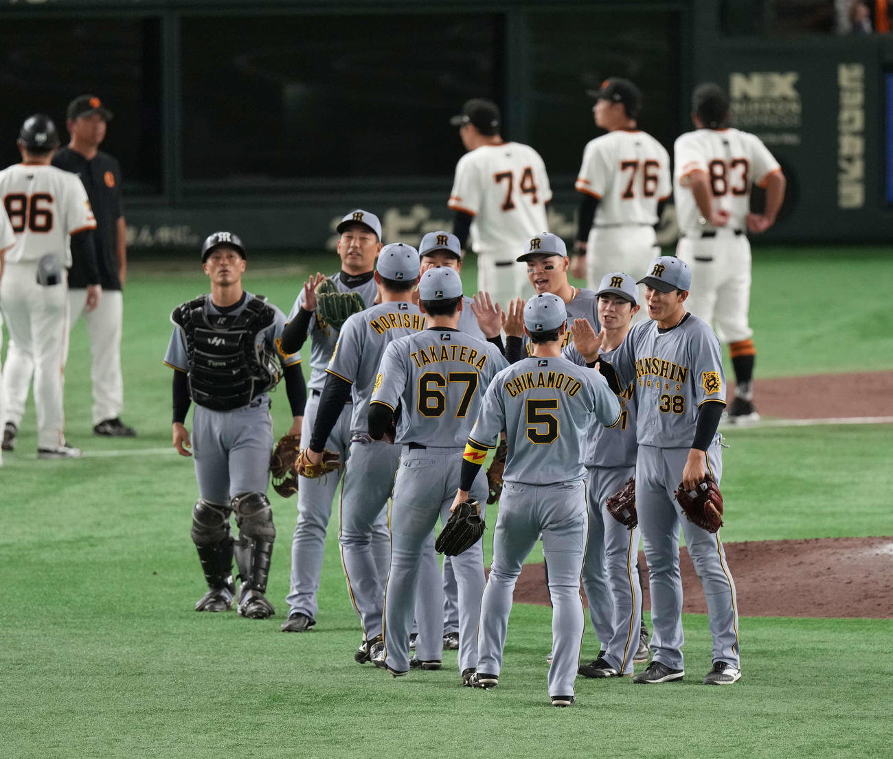 巨人対阪神　勝利のタッチをかわす佐藤輝（中央）ら阪神ナイン（撮影・井上学）
