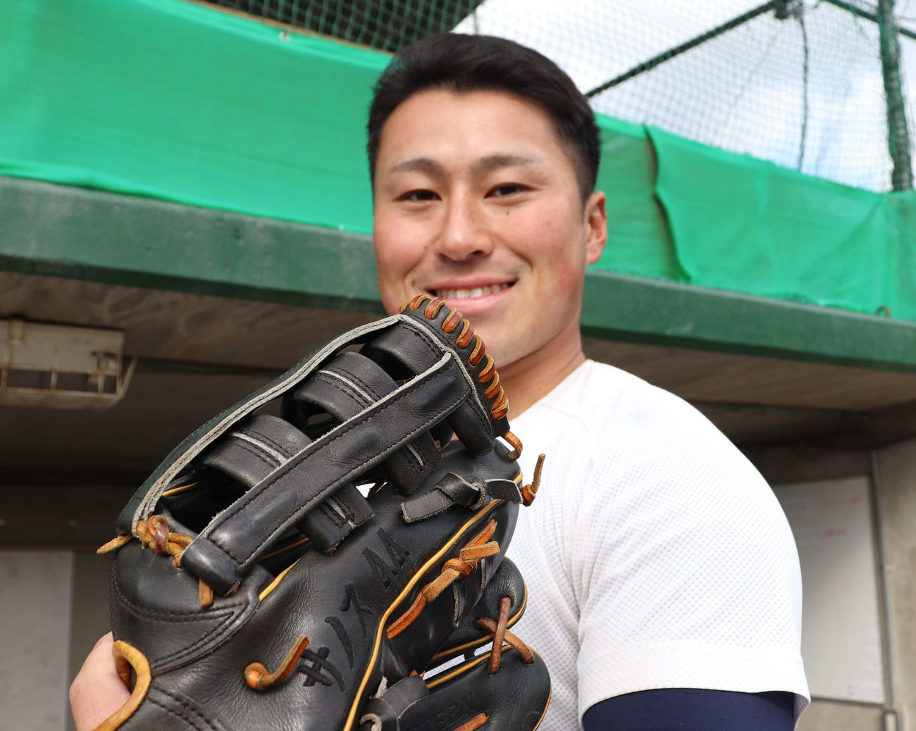 大商大時代にお気に入りのグラブと写真に収まる、当時大学3年生の西武渡部聖弥。大学時代は黒字で「サノス　44」の刺しゅうが施されている広陵の先輩・DeNA佐野恵太のグラブを練習で使用していた（2024年1月27日撮影）